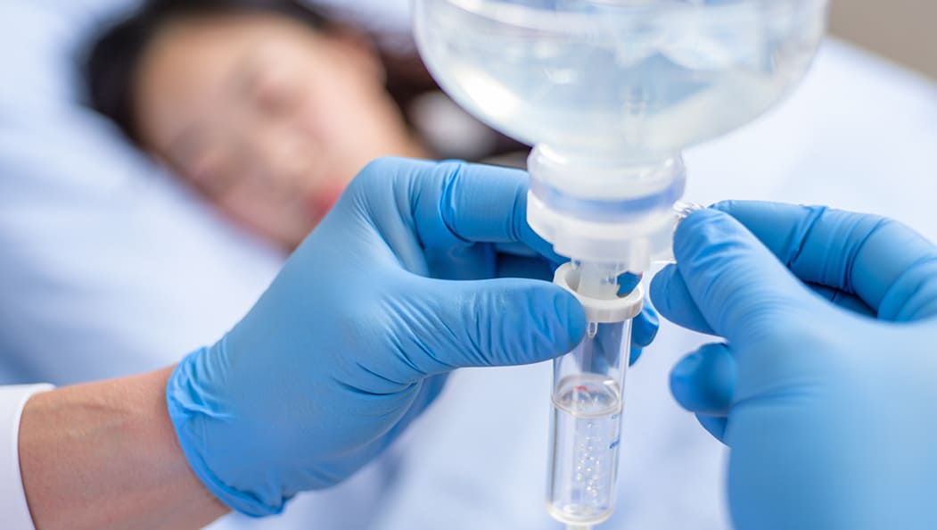 Крупный план рук врача, регулирующего скорость капельницы